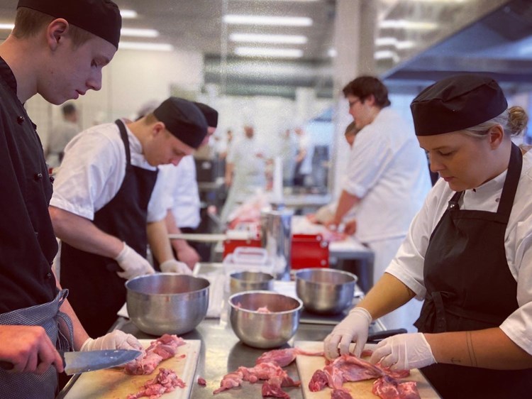 Slagterelever arbejder med udskæring af kød
