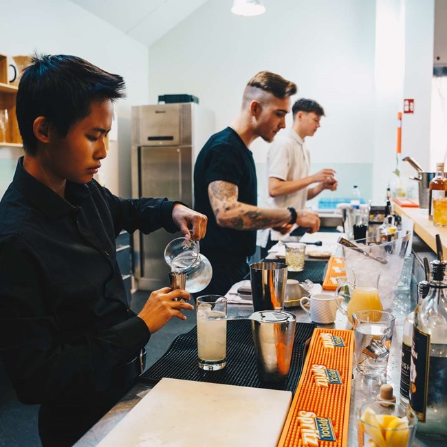 Tjenerelever laver cocktails.