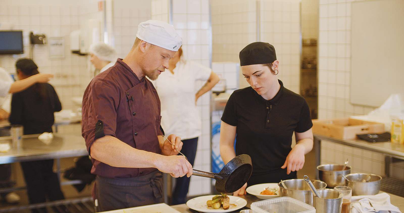 Underviser på Hotel- og Restaurantskolen anretter mad med elev