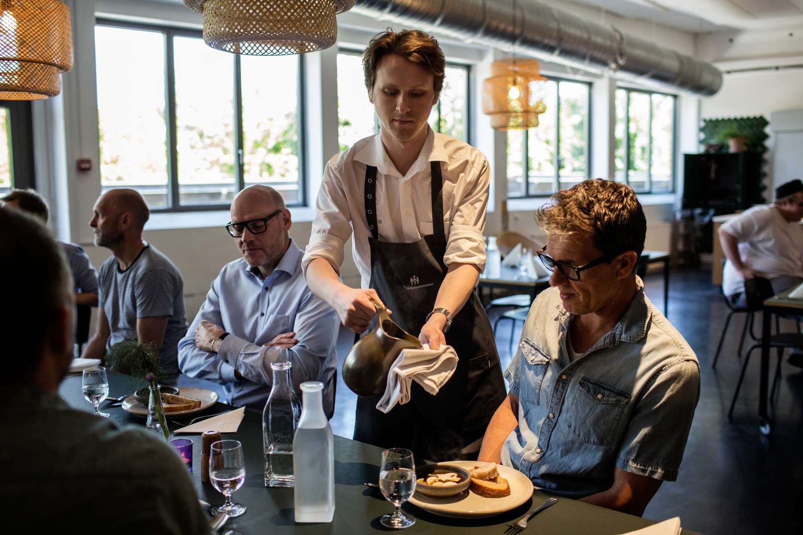Tjener anretter tallerken med sauce i Restauranten på Hotel- og Restaurantskolen.