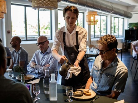 Tjener anretter tallerken med sauce i Restauranten på Hotel- og Restaurantskolen.