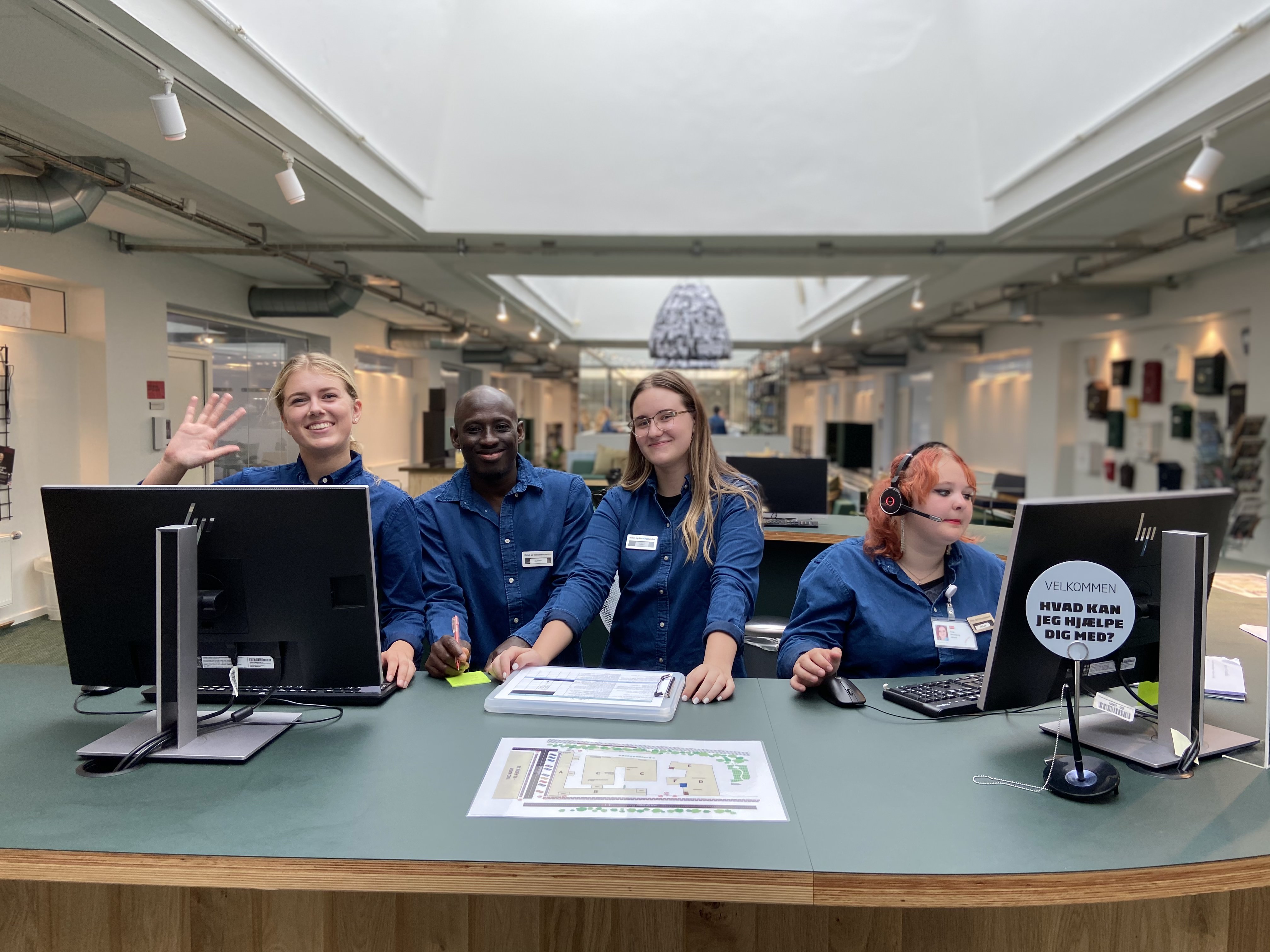 Receptionistelever smiler i skolens lobby.