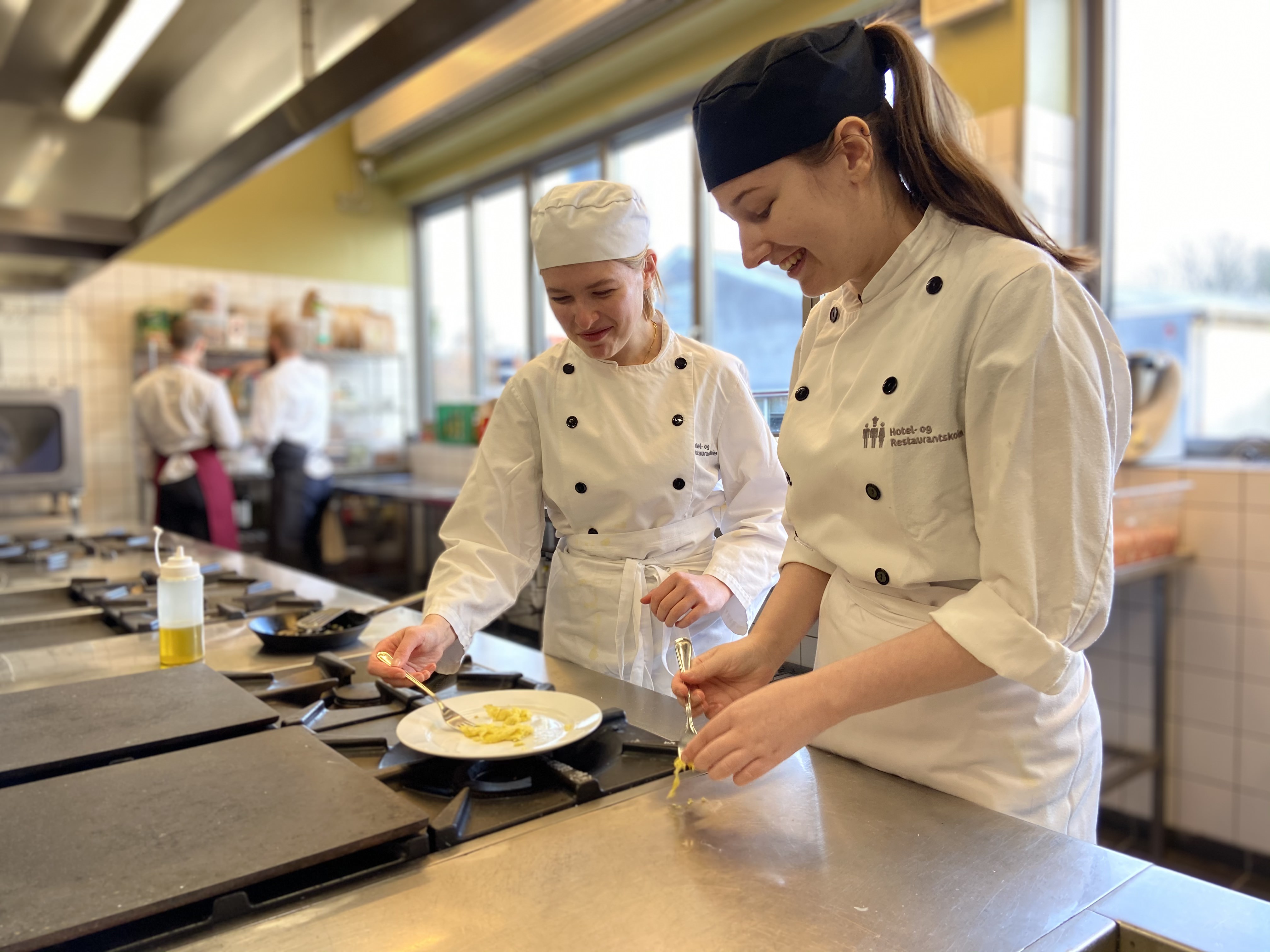 Elever i skolepraktik laver mad i køkkenet.